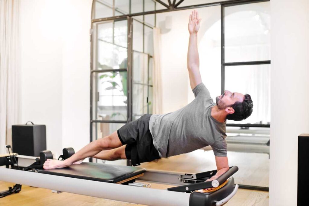 Man doing a side plank elbow stretch exercise in Pilates class