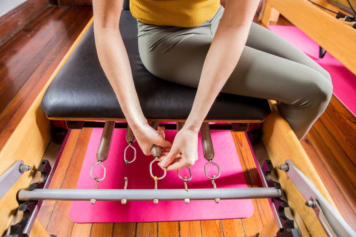 A woman sets up her leg springs in the pilates studio