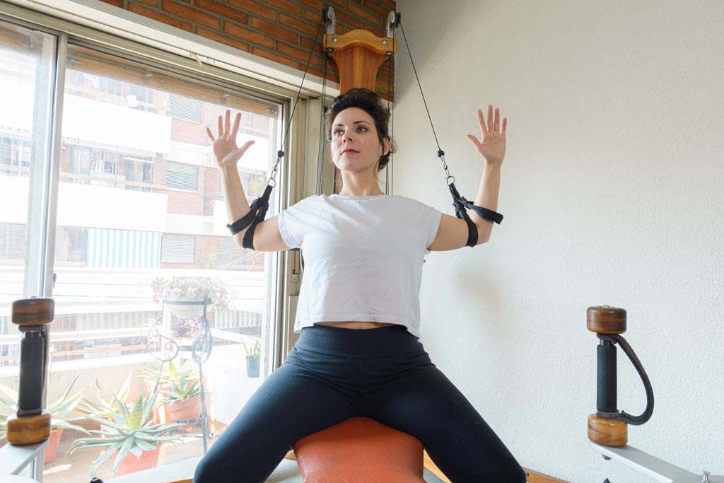 Front view of a woman completing upper body series movements on a gyrotonic machine.