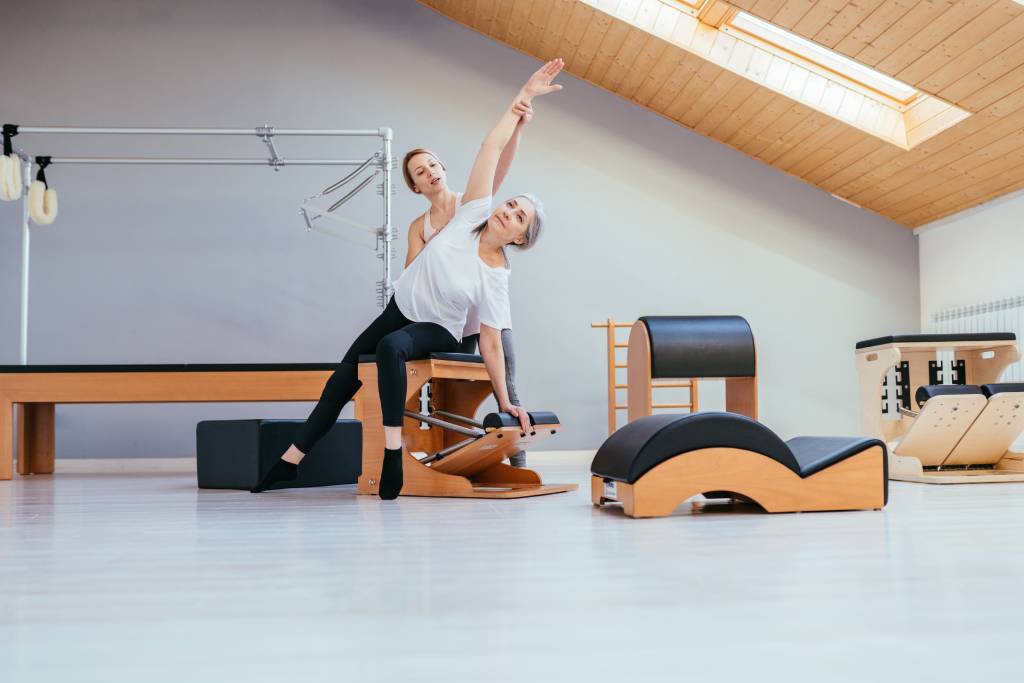 A woman doing Pilates exercises with a trainer