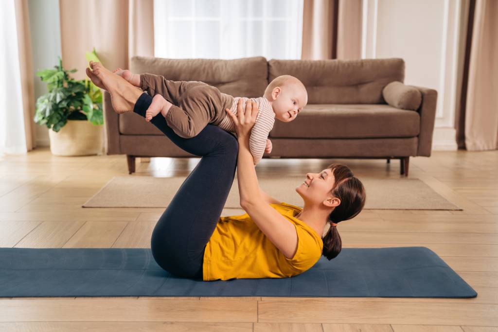 A mom lifting her baby on a yoga mat